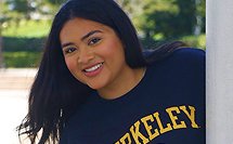Young woman with long dark hair smiling and wearing a black Berkeley t-shirt.